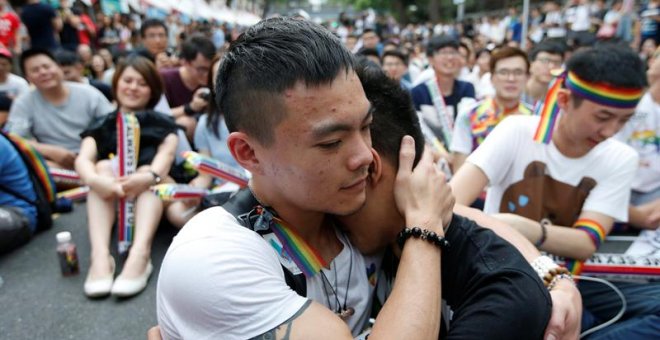 Dos integrantes de la comunidad LGBT (lesbianas, gais, bisexuales y transexuales) se abrazan mientras celebran la decisión del Tribunal Constitucional sobre el matrimonio entre personas del mismo sexo ante el Parlamento en Taipei / EFE