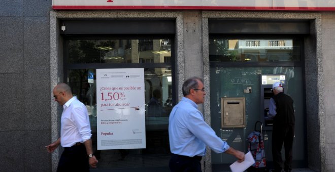 Varios transeuntes pasan junto a una oficina del Banco Popular en Madrid. REUTERS/Juan Medin