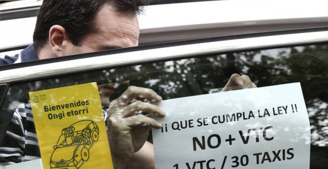 Un taxista pega en su taxi un cartel de protesta contra el incumplimiento de la proporción 1/30 entre licencias VTC y taxi. EFE