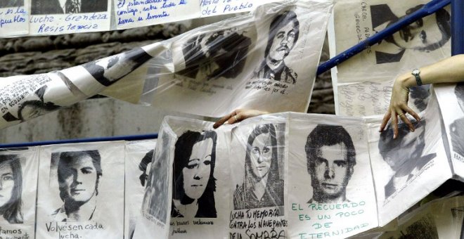 Una mujer cuelga fotografías de desaparecidos durante la última dictadura militar, alrededor de la Piramide de Mayo frente a la Casa de Gobierno, en Buenos Aires, Argentina, el 10 de diciembre de 2003, cuando se cumplen 20 años del retorno de éste país a