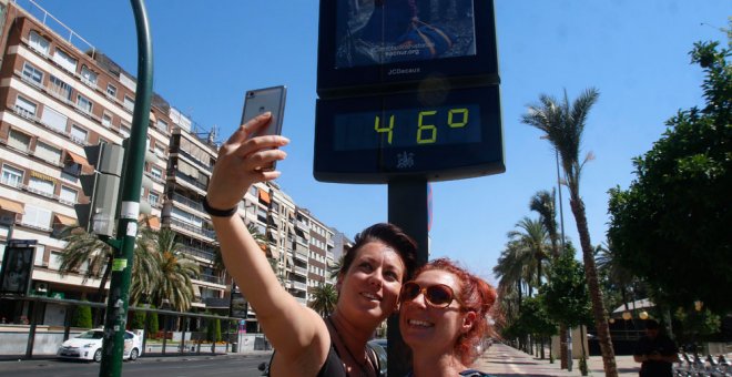 Dos mujeres se fotografían en Córdoba con un termómetro que marca 45 grados en la ciudad. EFE