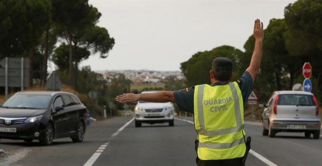 Un Guardia Civil desvía el tráfico tras el corte de la carretera de acceso a la localidad de Matalascañas, por el incendio de Moguer. /EFE