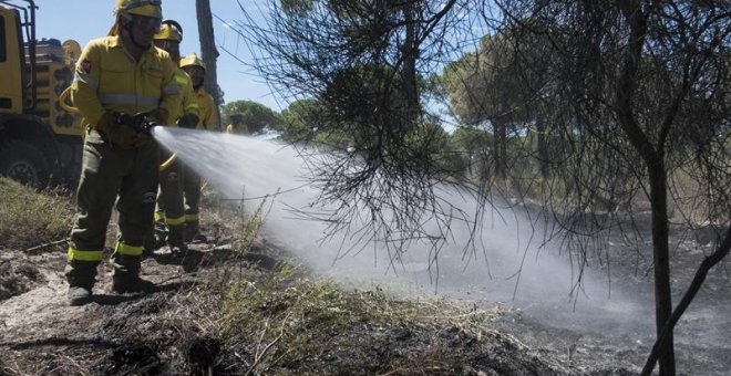 Efectivos del Infoca realizan labores de refresco tras el incendio forestal declarado el pasado sábado en el paraje "La Peñuela" de Moguer (Huelva), que ha afectado a una amplia superficie de masa forestal del entorno de Doñana e incluso parte del parque
