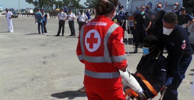 Trabajadores de la Cruz Roja ayudan a desembarcar a los 402 inmigrantes rescatados en el Mediterraáneo a su llegada al puerto de Brindisi (Italia). /EFE