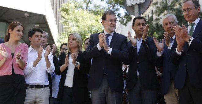 El presidente del Gobierno y del PP, Mariano Rajoy, junto a Marimar Blanco y otros dirigentes del PP en el despliegue de la pancarta en la sede del partido. | JUAN CARLOS HIDALGO (EFE)