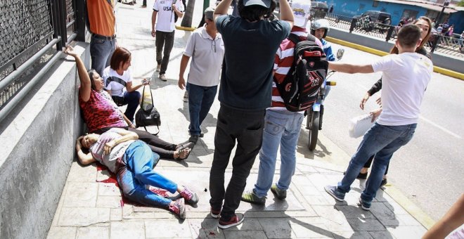 os mujeres yacen en el suelo durante un enfrentamiento entre un grupo de personas adeptas al oficialismo y personas opositoras al gobierno nacional durante la consulta popular hoy, domingo 16 de julio de 2017, en el oeste de Caracas (Venezuela). Dos perso