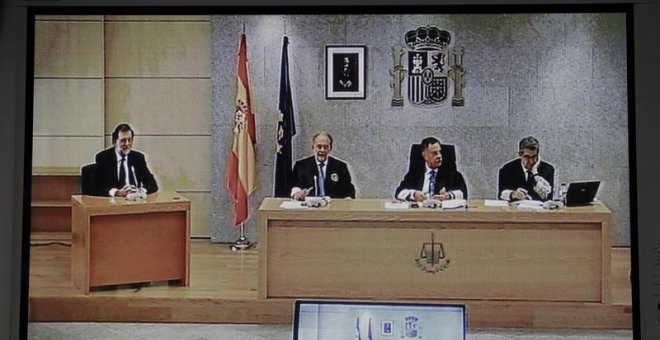 Imagen del monitor de la sala de prensa de la Audiencia Nacional de San Fernando de Henares del presidente del Gobierno, Mariano Rajoy (i). /EFE