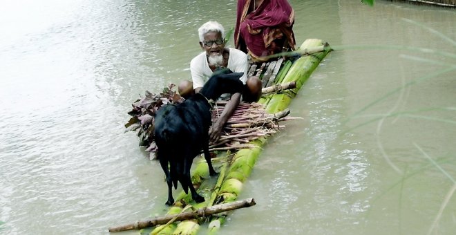 Una pareja bangladesí con una cabra navegan por las aguas de una gran inundación en el sur del país en busca de refugio AFP PHOTO/ Farjana K. GODHULY