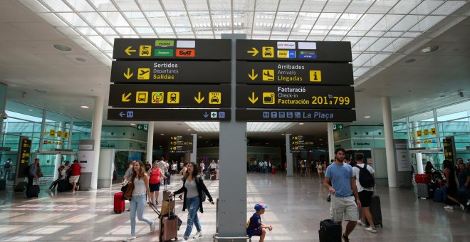 Viajeros junto a uno de los paneles informativos del Aeropuerto Barcelona-El Prat. REUTERS/Albert Gea