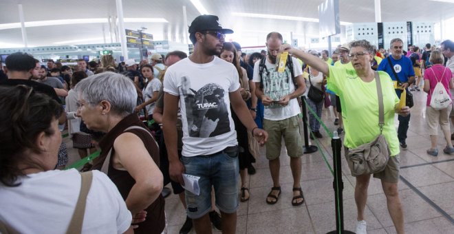 Miembros de la Asamblea Nacional de Cataluña (ANC) repartiendo folletos en el Aeropuerto de Barcelona-El Prat culpando al Estado de las colas que se han formado en las dos últimas semanas en los controles de seguridad del aeropuerto. EFE/Quique García
