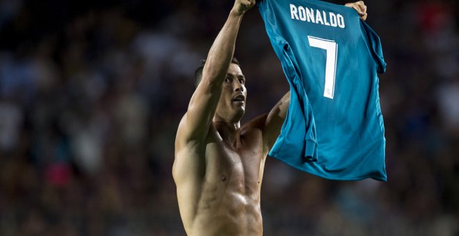 El jugador del Real Madrid Cristiano Ronaldo muestra su camiseta a los aficionados del Nou Camp, tras marcar el 1-2 de la ida de la Supercopa, lo que le valió la primera tarjeta amarilla. STRINGER / AFP