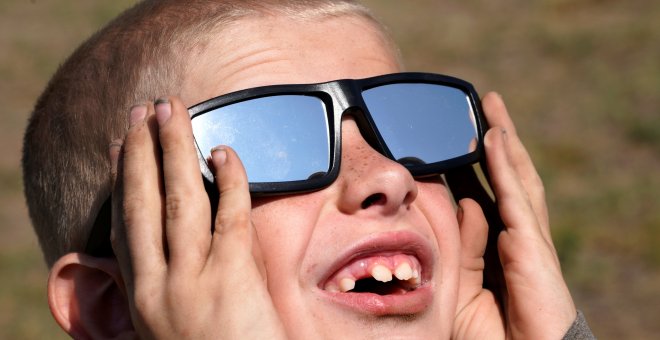 Un niño con unas gafas de sol especiales para observar el eclipse de Sol. REUTERS/Rick Wilking