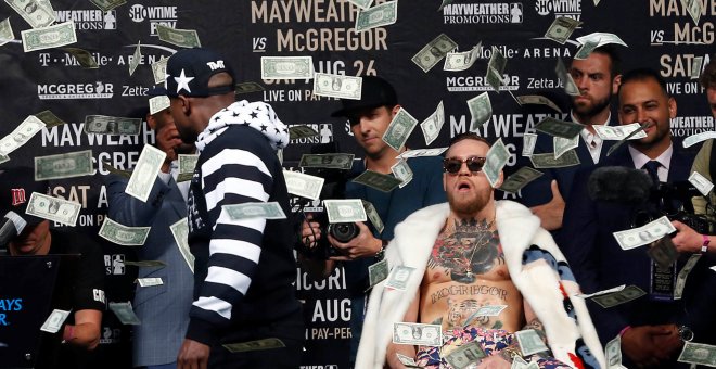 Mayweather arroja un fajo de billetes a la cara de McGregor durante uno de los careos para la promoción del combate.REUTERS/Noah K.Murray