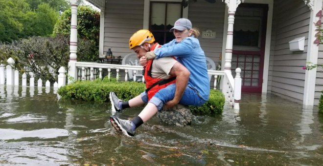 Un guarda ayuda a una mujer en las inundaciones en Houston por Harvey. REUTERS