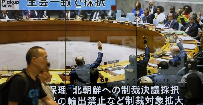 Peatones caminan en Tokio frente a una enorme pantalla que muestra un programa de noticias de televisión que informa sobre la sesión del Consejo de Seguridad de la ONU en Nueva York que acordó sanciones contra Corea del Norte. EFE/KIMIMASA MAYAMA