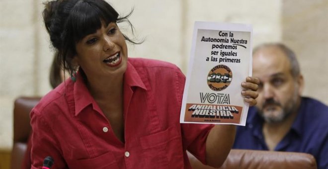 La portavoz de Podemos, Teresa Rodríguez, muestra un cartel en una de sus intervenciones durante la sesión de control al Gobierno que ha tenido lugar hoy en el Parlamento de Andalucía en Sevilla. /EFE