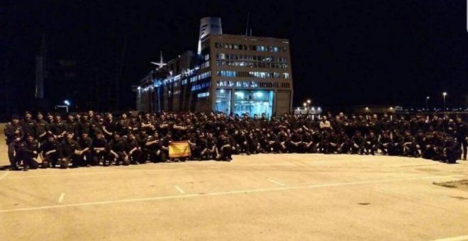 La Policía Nacional posando, con bandera de España incluida, al lado del crucero en el que se alojan en Barcelona. (@PortuariosCNT)