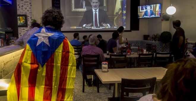Varias personas miran el discurso del rey Felipe VI en un bar en Barcelona, al final de la jornada de paro general en protesta por la actuación policial durante el referéndum del 1-O. EFE/Quique García