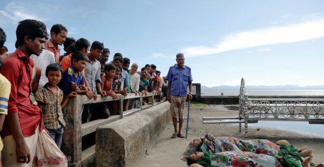 Varias personas observan los cadáveres de los refugiados rohinyás fallecidos este lunes en Bangladesh. /REUTERS