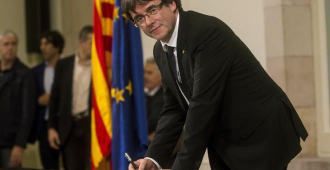 Puigdemont firma el documento de adhesión a la República catalana después de comparecer ante el pleno del Parlament para trasladar los resultados de la jornada del 1-O. | QUIQUE GARCÍA (EFE)