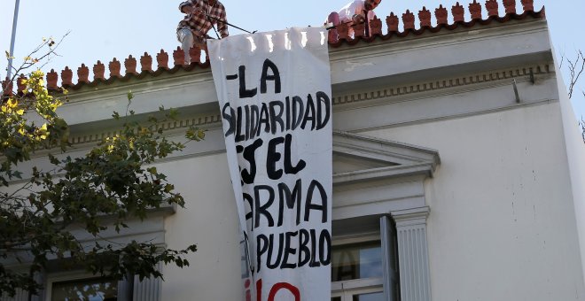 Empleados de la embajada española en Atenas retiran la pancarta "La solidaridad es el arma del pueblo". /REUTERS