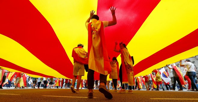 Varias personas bajo una gigantesca bandera catalana en la marcha en Barcelona por el día de la Fiesta Nacional. REUTERS/Gonzalo Fuentes