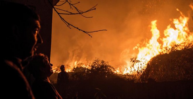 Los incendios están afectando especialmente a Galicia, donde han muerto cuatro personas. En la imagen, unos vecinos observan como se acerca a sus casas el incendio forestal de Carballeda de Avia (Ourense). - EFE