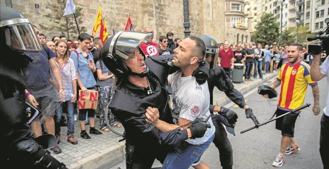La policía forcejea con uno de los agresores durante la manifestación del 9-O en Valencia. - EFE