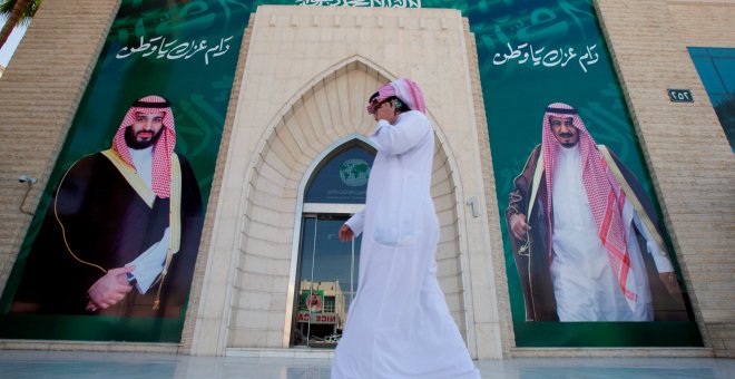 Un hombre caminando en Arabia Saudí entre los carteles con la imagen del rey Salman bin Abdulaziz y del príncipe heredero Mohammed bin Salman. /RETUERS