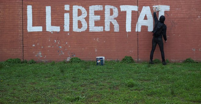 Un hombre pinta en un muro la palabra "LLIBERTAD" en Barcelona.REUTERS/Albert Gea
