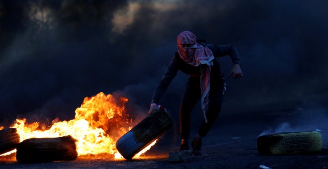 Un palestino sujeta un neumático en llamas durante las protestas producidas tras el reconocimiento de Jerusalén como capital de Israel por parte de Trump./REUTERS