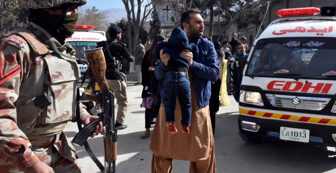 Un hombre sostiene a un niño ante un militar tras el ataque a una iglesia metodista en Pakistán. /EFE