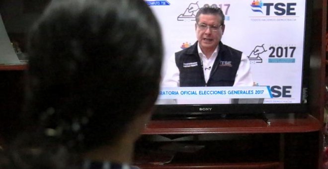 Un mujer escucha un discurso del magistrado presidente del Tribunal Supremo Electoral (TSE) David Matamoros, a través de un canal nacional de televisión en Tegucigalpa (Honduras). EFE/Gustavo Amador