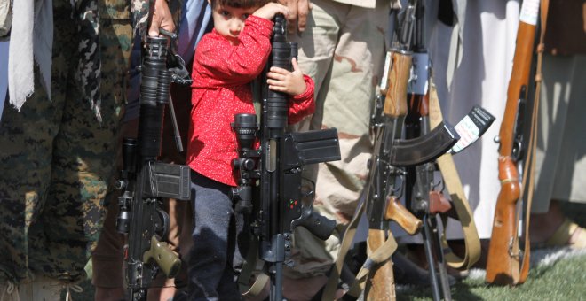 Un niño descansa apoyado sobre un arma en Yemen./REUTERS