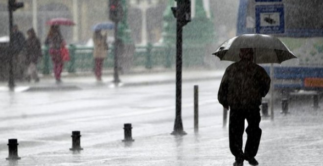 Foto de archivo de un hombre que camina bajo la lluvia en San Sebastián. / EFE