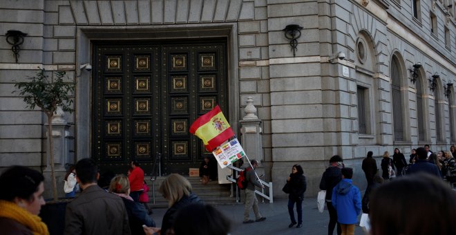Un hombre con la bandera española y una pancarta junto a la sede del Banco de España en Barcelona. REUTERS/Jon Nazca