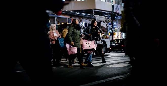 Dos personas cruzan la calle cargando bolsas a la salida de unos grandes almacenes en Nueva York./EFE