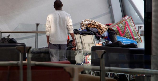 Uno de los zimbabuenses varados en el aeropuerto de Bangkok desde el pasado 23 de octubre, de espaldas en la terminal de salidas en el aeropuerto Suvarnabhumi de Bangkok.- EFE