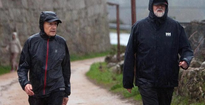 Mariano Rajoy, a la derecha de la imagen, camina bajo la lluvia acompañado del marido de Ana Pastor. |  SALVADOR SAS (EFE)