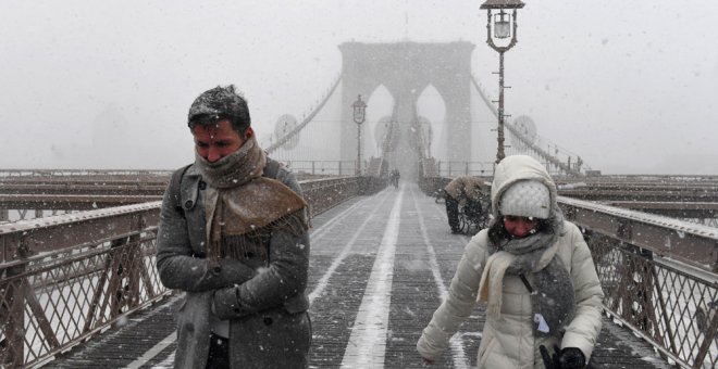 Varias personas caminan por el puente de Brooklyn, en Nueva York, en medio de la peor tormenta de la temporada en EEUU, que ha afectado a todo el noroeste del país.	REUTERS/Darren Ornitz