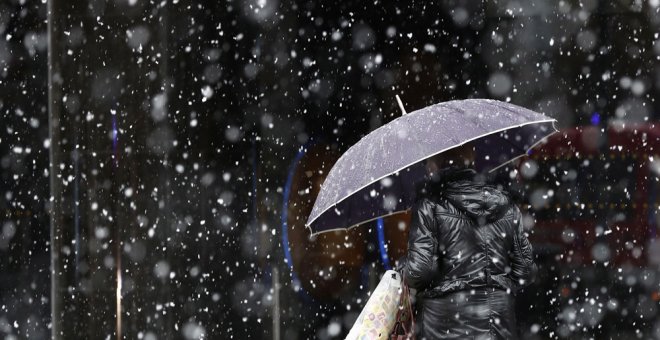Una mujer camina bajo la nieve en Pamplona. EFE