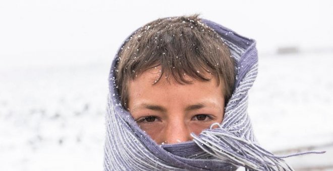 Un joven refugiado sirio se cubre para protegerse del frío en el valle de la Bekaa, en el Líbano, en enero de 2016.-  ACNUR/UNHCR/Haidar Darwish.