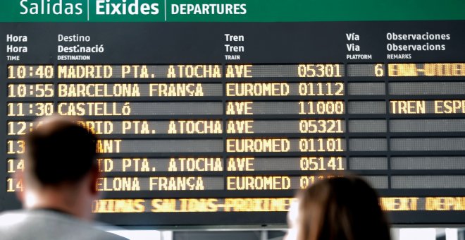 Dos pasajeros observan el horario del AVE a Castellón en el panel de salidas de la estación Joaquín Sorolla de València. EFE/Manuel Bruque