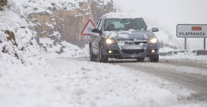 Un coche circula por la CV15 en el Coll d'Ares cuando la nieve ha cubierto el interior de la provincia de Castellón. /EFE