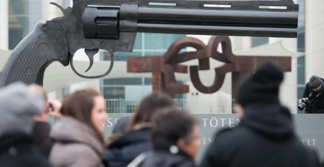 La gente mira un arma de gran tamaño colocada por activistas pacifistas frente a la Cancillería Federal en Berlín. AFP