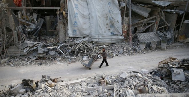 Un hombre empuja un carro por los edificios dañados en la ciudad sitiada de Duma, Guta Oriental, Damasco. REUTERS / Bassam Khabieh