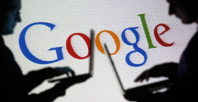 Varias personas con sus ordenadores frente a una proyección del logo de Google. REUTERS