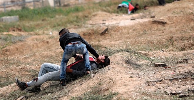 Un palestino ayuda a un compañero herido durante los enfrentamientos con soldados israelíes en el este de Beit Hanun, norte de la Franja de Gaza.-  EFE/Mohammed Saber