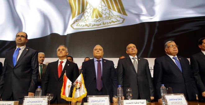 El jefe de la Comisión Nacional Electoral egipcio (NEC), Lasheen Ibrahim (c), y otros miembros no identificados, permanecen de pie antes de ofrecer una rueda de prensa en la que anuncian los resultados finales de las elecciones presidenciales, en El Cair