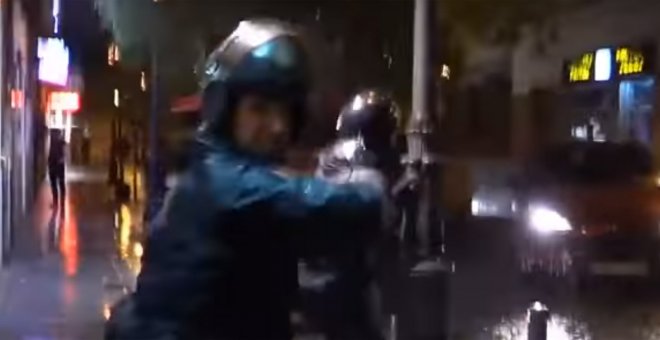 Momento en el que un agente de policía golpea la mano de otro otro agente que se cruza en su camino